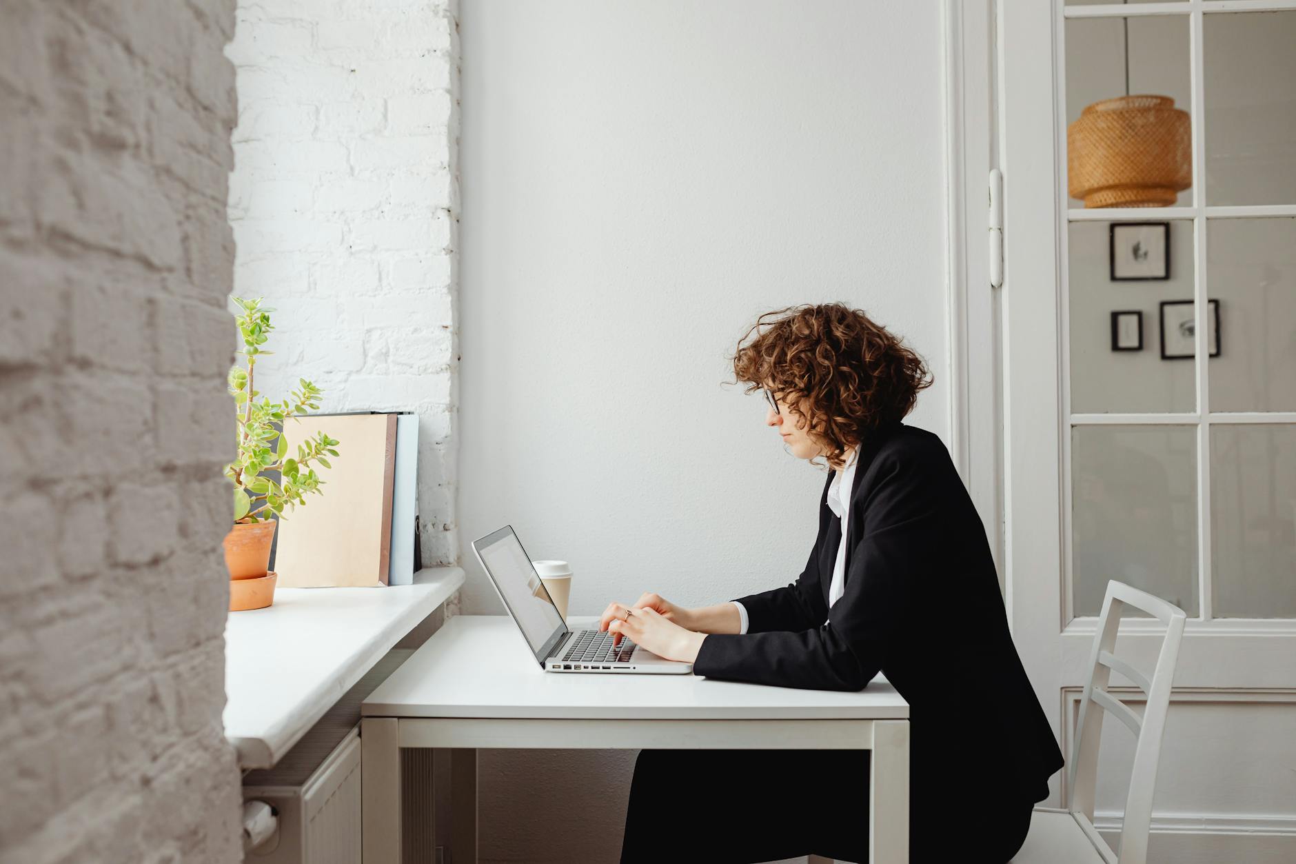 woman in black long blazer using a laptop